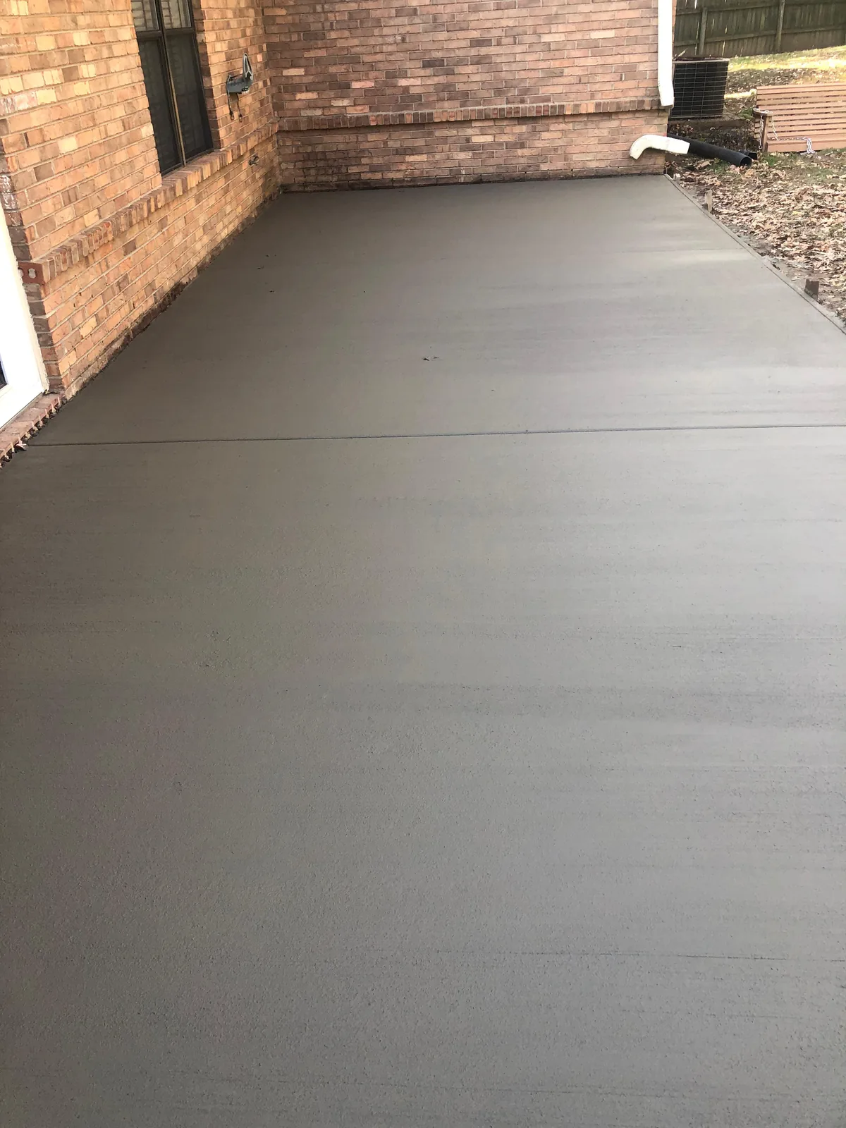 Fresh concrete patio finished clean against a brick house