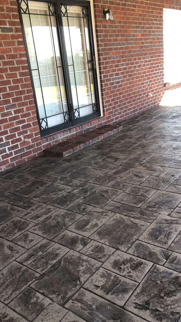 Cobblestone-stamped covered patio behind a brick home